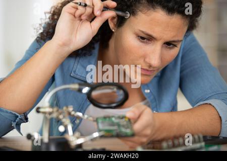 jeune femme réparant l'atelier de réparation de téléphone portable Banque D'Images