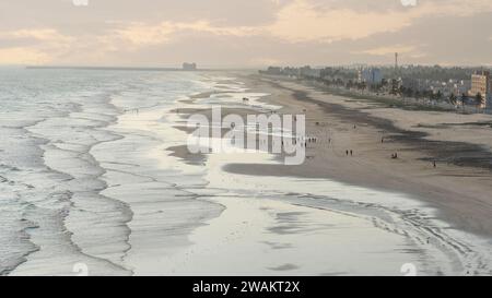 Taqah, salalah- 12 décembre 2023 : personnes jouant au football sur la plage au coucher du soleil Banque D'Images