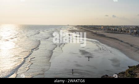 Taqah, salalah- 12 décembre 2023 : personnes jouant au football sur la plage au coucher du soleil Banque D'Images