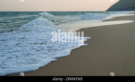 Plage de sable et mer bleue. De près, une vague douce a jalonné la plage de sable. Belles vagues de mer avec mousse de couleur bleue et turquoise isolée. Océan puissant Banque D'Images