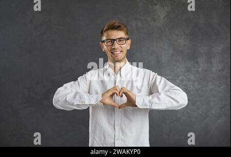 Portrait en studio d'un jeune homme heureux formant un symbole en forme de coeur avec ses mains Banque D'Images