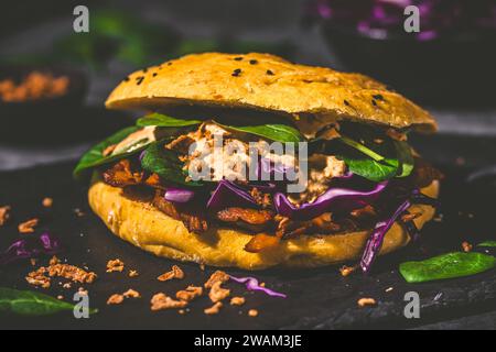 Hamburger végétalien fait maison dans du pain plat à la citrouille fourré de viande de soja, de chou rouge, d'épinards et de sauce à la citrouille. Banque D'Images