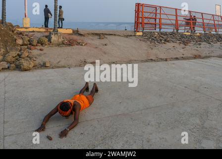 Ayodhya, Inde. 26 décembre 2023. Un dévot hindou accomplit des rituels en s'allongeant sur la route sur les rives de la rivière Sarayu. L'ancienne ville d'Ayodhya se trouve sur les rives de la rivière Sarayu et est le lieu de naissance du Seigneur RAM et est considérée comme très religieuse. (Photo de Biplov Bhuyan/SOPA Images/Sipa USA) crédit : SIPA USA/Alamy Live News Banque D'Images