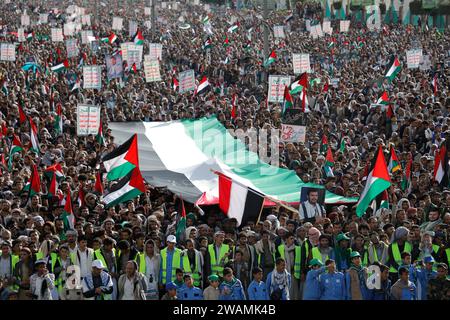 Sanaa, Yémen. 5 janvier 2024. Les manifestants brandissent des pancartes et brandissent un drapeau palestinien géant lors d'une marche en solidarité avec le peuple de Gaza. Vendredi, des milliers de personnes se sont ralliées en soutien à Gaza dans la capitale yéménite contrôlée par les rebelles, Sanaa, criant des slogans anti-américains et anti-israéliens. (Image de crédit : © Osamah Yahya/ZUMA Press Wire) USAGE ÉDITORIAL SEULEMENT! Non destiné à UN USAGE commercial ! Crédit : ZUMA Press, Inc./Alamy Live News crédit : ZUMA Press, Inc. Crédit : ZUMA Press, Inc./Alamy Live News Banque D'Images