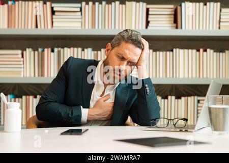 Homme fatigué ayant un mal de tête terrible. Homme épuisé se sentant malsain, bouleversé au sujet de la maladie de mal de tête. Homme d'âge moyen stressé souffrant de maux de tête Banque D'Images
