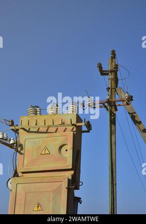 Vieux et obsolètes de transformateur électrique dans le contexte d'un ciel bleu. Dispositif pour la distribution de fourniture de l'énergie à haute tension Banque D'Images