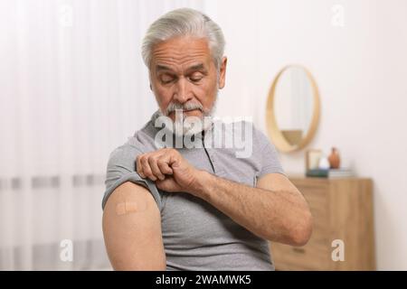 Homme âgé avec bandage adhésif sur le bras après vaccination à domicile Banque D'Images