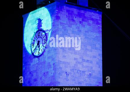 Latina, Italie. 5 janvier 2024. L'ombre du Befana volant projeté sur la tour de la mairie de Latina à l'occasion des célébrations de l'Epiphanie. Des centaines d'enfants et d'adultes acclamés ont accueilli le Befana qui est descendu de la tour de la mairie à l'occasion des célébrations de l'Epiphanie en Latina. Crédit : ZUMA Press, Inc./Alamy Live News Banque D'Images