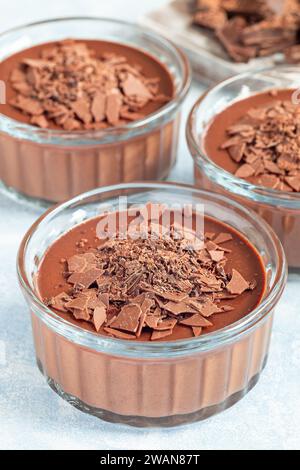Dessert Panna Cotta au chocolat en ramequin en verre, planche de bois et fond de chocolat cassé, vertical Banque D'Images