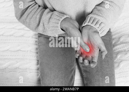 Femme souffrant d'un doigt de déclenchement, gros plan. Photo noir et blanc avec accent rouge Banque D'Images