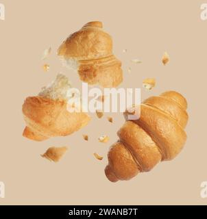 Délicieux croissants frais tombant sur fond beige Banque D'Images