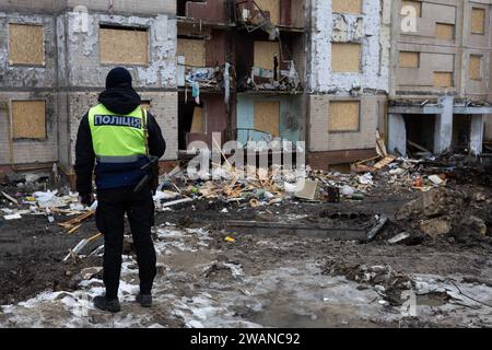Kiev, Ukraine. 05 janvier 2024. Un officier de police regarde un immeuble résidentiel endommagé par une attaque de missiles russes à Kiev. Au moins 27 personnes ont été hospitalisées et une femme âgée blessée est morte dans une ambulance après un incendie dans un bâtiment de plusieurs étages à la suite d'une attaque à la roquette à Kiev le 2 janvier 2024. (Photo Oleksii Chumachenko/SOPA Images/Sipa USA) crédit : SIPA USA/Alamy Live News Banque D'Images