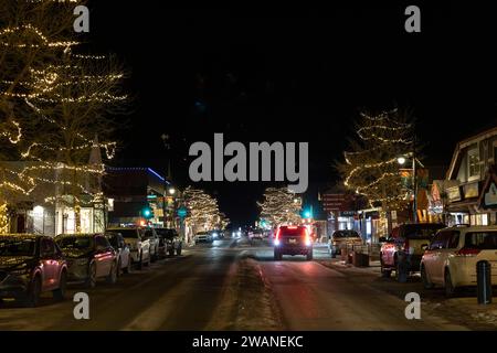 Canmore, Alberta, Canada. En regardant vers l'ouest, les boutiques et les lumières le long de la 8e Avenue du centre-ville près de la 6e Avenue/Marra's Way un soir d'hiver. Banque D'Images