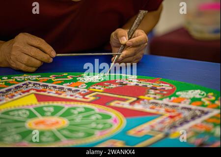 Photo de gros plan à mise au point sélective d'un moine bouddhiste tibétain mains alors qu'il travaille sur la création d'un mandala sacré ou peinture sur sable. Banque D'Images