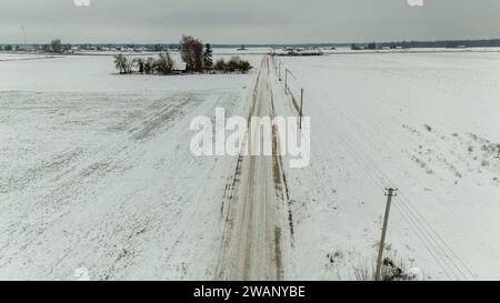 Photographie de drone de petite route de terre rurale pendant la journée nuageuse d'hiver Banque D'Images