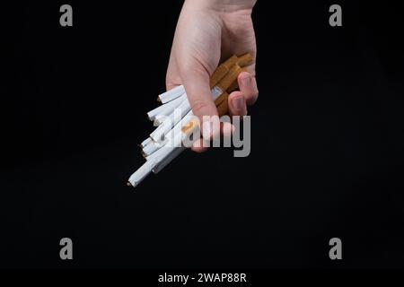 La main est de donner des paquet de cigarettes sur fond noir Banque D'Images