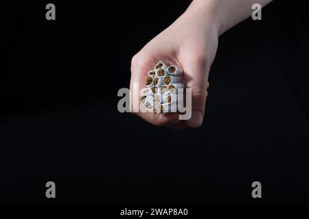 La main est de donner des paquet de cigarettes sur fond noir Banque D'Images