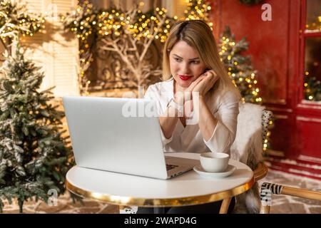 Adulte souriant sur la conférence en ligne d'appel vidéo à noël. Fête jeune femme parlant à des amis et la famille sur ordinateur portable pour l'hiver saisonnier Banque D'Images