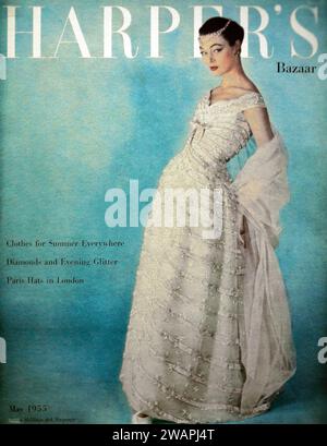 Harper's Bazaar mai 1955 couverture | cette image enchanteresse montre une femme exhalant grâce et sophistication alors qu'elle arbore une robe blanche resplendissante. Banque D'Images