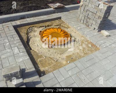 Pose de dalles de pavage autour du regard d'égout Banque D'Images