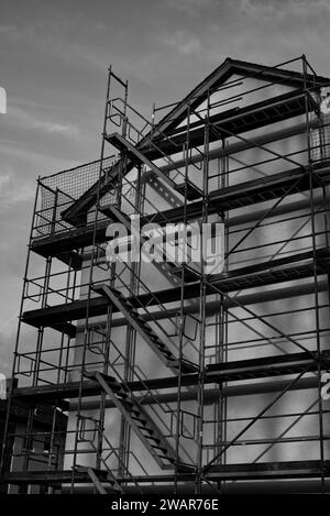 construction complète d'échafaudage à la façade d'une maison en noir et blanc Banque D'Images