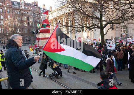 Manchester, Royaume-Uni. 6 janvier 2024. Manchesters Santa toujours en place alors que les manifestants à Manchester Royaume-Uni protestent contre la guerre à Gaza. Manifestation palestinienne dans le centre de Manchester. ROYAUME-UNI. Plus de deux mille manifestants se sont rassemblés sur la place Saint-Pierre pour réclamer un cessez-le-feu. Ils ont ensuite marché à travers le centre-ville. La police a gardé des points de vente qui, selon les manifestants, avaient des liens avec Israël, notamment Barclays Bank et Starbucks Coffee. Les manifestants brandissaient des drapeaux et portaient des pancartes avec des slogans contre la guerre. Manchester UK. Photo : garyroberts/worldwidefeatures.com crédit : GaryRobertsphotography/Alamy Live News Banque D'Images