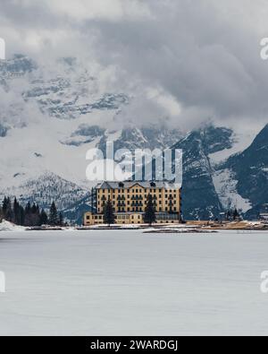 Un majestueux bâtiment de grande hauteur est niché sur une montagne enneigée en toile de fond dans un paisible pays des merveilles hivernales Banque D'Images