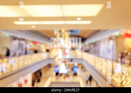 Shopping de Noël : scène floue dans un centre commercial à plusieurs niveaux avec éclairage de Noël Banque D'Images