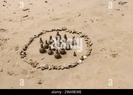 Une belle scène de plage présentant un visage de galets souriant créé sur le sable, avec une toile de fond du vaste océan qui s'étend à l'horizon Banque D'Images