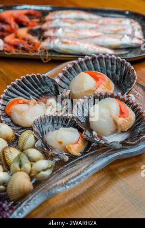 Trois assiettes blanches présentant une variété de succulents fruits de mer, y compris des coquilles Saint-Jacques et des crevettes Banque D'Images