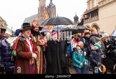 Une foule, portant des couronnes de papier et des vêtements régionaux marchent avec un acteur se faisant passer pour l'un des Sages alors qu'ils participent à une pièce de la Nativité publique jouée dans la rue de la vieille ville de Cracovie, en Pologne, le 6 janvier 2024. Le 6 janvier est la fête des trois rois polonais, lorsque des célébrations de masse ont lieu et que le jeu de la Nativité est joué par les acteurs avec les membres du public. Les célébrations ont le caractère d'une fête familiale. Plus de 800 villes ont joué la pièce en Pologne cette année. Des centaines de personnes ont assisté au festival malgré le temps froid et pluvieux. Banque D'Images