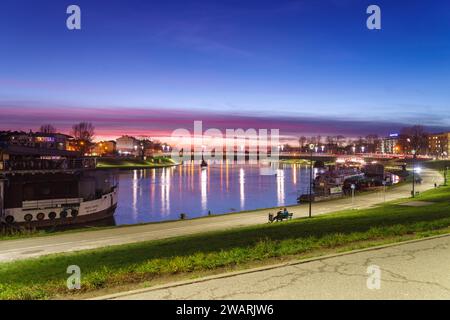 CRACOVIE, POLOGNE - 27 DÉCEMBRE 2023 : coucher de soleil sur la rivière Wisla en direction du pont Debnicki Banque D'Images