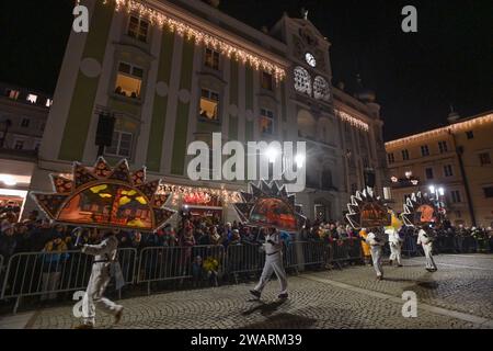 Dreikönigsingen und Glöcklerlauf am Rathausplatz in Gmunden, im oberösterreichischen Salzkammergut, am 05.01.2024. Sowohl das Dreikönigssingen als auch der Glöcklerlauf sind alte, eingeprägte Brauchtumsveranstaltungen im Salzkammergut in Österreich. Während des Glöcklerlaufs tragen junge Burschen prächtig geschmückte Laternenkappen mit meist lokalen Motiven am Kopf. Dabei wird durch laufen, springen und tanzen, mit an Gürteln der weiß Gekleideten angebrachten Glocken, entsprechend Lärm gemacht und dazu gesungen damit treiben die Glöckler in der letzten Rauhnacht der saison, dem 5,1. eines jede Banque D'Images