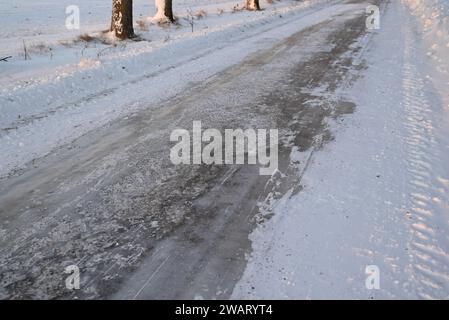 Route glacée dans la campagne, avec des marques de gravier et de rayures de chasse-neige. Banque D'Images