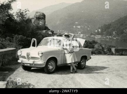 Femme habillée en blanc et Alfa Romeo Giulietta Ti voiture sur la route, Rome, Italie années 1960 Banque D'Images