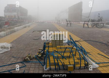 Des pavés sont posés sur un trottoir nouvellement construit un matin brumeux avant la visite du Premier ministre indien Narendra Modi à Ayodhya. Ramnagari Ayodhya, autrefois connu pour ses rues étroites et ses routes en décomposition, progresse régulièrement : toutes les routes et bâtiments menant à RAM Janmabhoomi sont en cours d’élargissement et de rénovation pour faciliter les déplacements. Banque D'Images