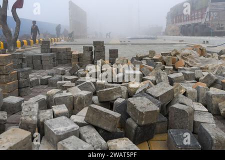 Des pavés sont posés sur un trottoir nouvellement construit un matin brumeux avant la visite du Premier ministre indien Narendra Modi à Ayodhya. Ramnagari Ayodhya, autrefois connu pour ses rues étroites et ses routes en décomposition, progresse régulièrement : toutes les routes et bâtiments menant à RAM Janmabhoomi sont en cours d’élargissement et de rénovation pour faciliter les déplacements. Banque D'Images