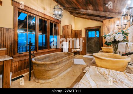 Une salle de bains élégante avec panneaux muraux en bois, comptoirs et poutres en bois naturel pour une ambiance intemporelle et rustique Banque D'Images