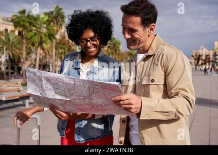 Couple touristique multiracial d'âge moyen à la recherche d'un emplacement en utilisant une carte papier. Banque D'Images