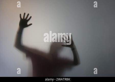 Homme avec la silhouette des mains levées derrière le verre dépoli Banque D'Images