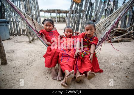 Jeunes filles Wayuu, portant les vêtements traditionnels vus se reposer dans un hamac avant de prendre part à la danse traditionnelle Yonna. Un groupe Wayuu de filles et un garçon dansent la Yonna pour les touristes qui visitent leur maison à Playa Camarones, à la Guajira, une zone désertique dans le nord de la Colombie. La Yonna, danse traditionnelle du peuple indigène Wayuu, est exécutée pour des célébrations, pour le Majayut (la transition d'une fille indigène à une femme), ou à des occasions liées à la spiritualité. Les femmes portent des robes traditionnelles rouges, tandis que les hommes portent une tenue typique appelée 'wayuuco'. Banque D'Images