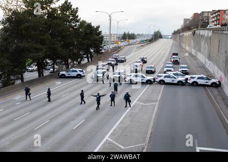 Seattle, Washington, États-Unis. 6 janvier 2024. Des membres du département de police de Seattle font la queue alors que les manifestants bloquent l'I-5 en direction du nord en solidarité avec la Palestine. Les manifestations hebdomadaires appelant à un cessez-le-feu immédiat se sont intensifiées depuis le déclenchement de la guerre entre Israël et les groupes militants palestiniens dirigés par le Hamas dans la bande de Gaza en octobre. Crédit : Paul Christian Gordon/Alamy Live News Banque D'Images