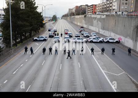 Seattle, Washington, États-Unis. 6 janvier 2024. Des membres du département de police de Seattle font la queue alors que les manifestants bloquent l'I-5 en direction du nord en solidarité avec la Palestine. Les manifestations hebdomadaires appelant à un cessez-le-feu immédiat se sont intensifiées depuis le déclenchement de la guerre entre Israël et les groupes militants palestiniens dirigés par le Hamas dans la bande de Gaza en octobre. Crédit : Paul Christian Gordon/Alamy Live News Banque D'Images