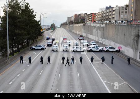 Seattle, Washington, États-Unis. 6 janvier 2024. Des membres du département de police de Seattle font la queue alors que les manifestants bloquent l'I-5 en direction du nord en solidarité avec la Palestine. Les manifestations hebdomadaires appelant à un cessez-le-feu immédiat se sont intensifiées depuis le déclenchement de la guerre entre Israël et les groupes militants palestiniens dirigés par le Hamas dans la bande de Gaza en octobre. Crédit : Paul Christian Gordon/Alamy Live News Banque D'Images