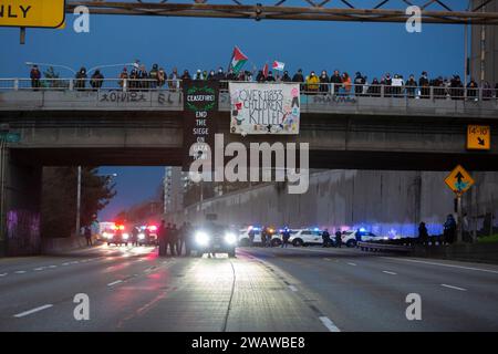 Seattle, Washington, États-Unis. 6 janvier 2024. Des membres du département de police de Seattle font la queue alors que les manifestants bloquent l'I-5 en direction du nord en solidarité avec la Palestine. Les manifestations hebdomadaires appelant à un cessez-le-feu immédiat se sont intensifiées depuis le déclenchement de la guerre entre Israël et les groupes militants palestiniens dirigés par le Hamas dans la bande de Gaza en octobre. Crédit : Paul Christian Gordon/Alamy Live News Banque D'Images