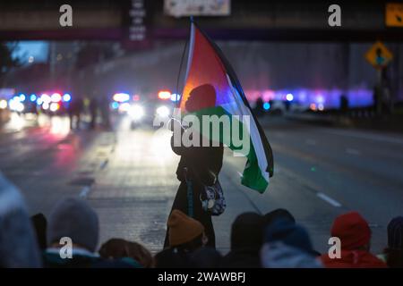 Seattle, Washington, États-Unis. 6 janvier 2024. Un homme agite un drapeau de Palestine alors que des manifestants bloquent l'I-5 en direction du nord en solidarité avec la Palestine. Les manifestations hebdomadaires appelant à un cessez-le-feu immédiat se sont intensifiées depuis le déclenchement de la guerre entre Israël et les groupes militants palestiniens dirigés par le Hamas dans la bande de Gaza en octobre. Crédit : Paul Christian Gordon/Alamy Live News Banque D'Images