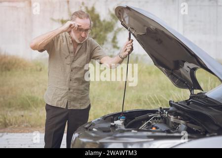La voiture de sexe masculin âgé senior cassée ont un problème de panne de moteur seul personne n'aide à ouvrir le capot pour l'auto-vérification sur le côté de la route. Banque D'Images