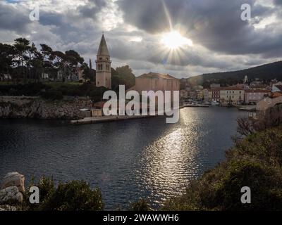 Soleil du matin brisant à travers les nuages, vue de l'entrée du port de Veli Losinj, avec St. Anthony's Church, île de Losinj, Kvarner Gulf Bay Banque D'Images