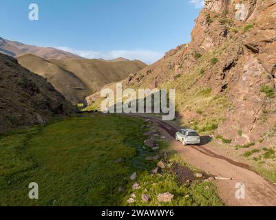 Vue aérienne, véhicule hors route sur route de gravier à travers une vallée de montagne, région de Naryn, Kirghizistan Banque D'Images