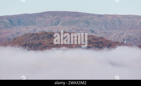 Cumbria, Royaume-Uni. 7 janvier 2024. UK Météo. Soleil brûlant la brume basse au-dessus du lac caché Windermere vu du village de Windermere le Lake District . Crédit : Gordon Shoosmith/Alamy Live News Banque D'Images